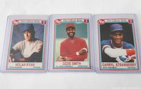 Three cards side by side in sleeves: Nolan Ryan, Ozzie Smith, Darryl Strawberry