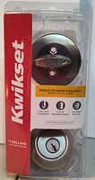 Front view of sealed Kwikset deadbolt package showing both exterior keyed cylinder and interior thumb-turn