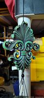 Close-up of cast fleur-de-lis weight showing verdigris finish