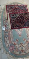 Oval aqua floral rug with two red mats placed on top