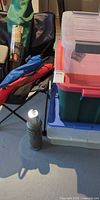 Open folding chair beside stack of plastic bins and thermos