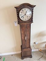 Full view of oak floor clock against wall