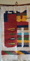 Upper section of colorful tapestry showing geometric pattern and hanging loop on rod