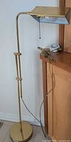 Full view of brass floor lamp beside cabinet