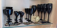Assorted black glass stemware with frame and ribbon on glass shelf