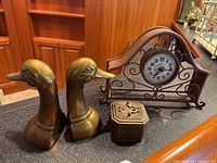 Lot overview showing pair brass duck head bookends, pierced brass box, copper scroll mantel clock