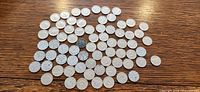 Full spread of about 70 Canadian nickels on table surface