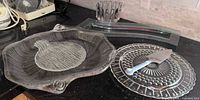 Group of all glass platters, bowl, and cake lifter on countertop