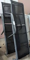 Two stacked metal frame black mesh loungers, front view