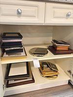 Cabinet shelves with stacks of wood, black and gold frames