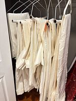 Multiple cream drapery panels on hangers in closet
