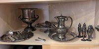 Shelf view of champagne bucket, trays, pedestal, shakers and utensils
