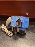 Front view of stained glass house lamp showing blue roof, window detail, cord