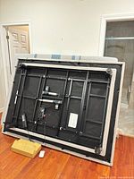 Underside of adjustable bed showing frame, actuators, legs, mattress edge, hardware box and remote