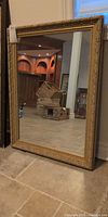 Full view of rectangular gold-framed mirror standing upright