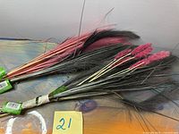 Bundle of pink/mauve and black faux pampas stems on table