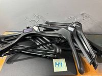 Pile of black plastic hangers on surface, various logos visible
