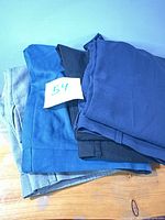 Stack of four folded dress pants in grey, blue and black hues
