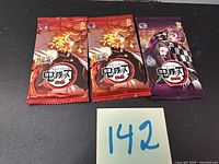 Front view of three sealed Demon Slayer trading card packs