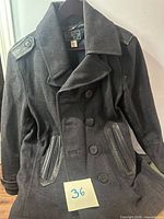 Full front view of black Diesel peacoat showing double-breasted button layout and zip pockets