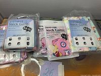 Front view of four sealed neck gaiter packages showing brands and graphics