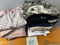 Stack of folded women’s tops showing patterned blouse and sweaters