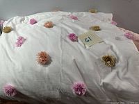 Top view showing white fabric with multicolor pom-poms