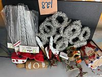 Assorted decorations including silver rings, craft picks, rolling pin, LED candles, greenery, red gift-box ornament