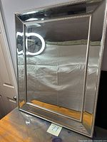 Full view of rectangular mirror with silver mirrored frame and beaded trim