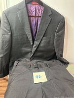 Jacket on hanger with matching pants displayed, charcoal color visible