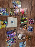 Overview of approximately 13 loose holographic Pokémon cards spread on wood surface