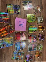 Overview of approximately 18 holographic Pokémon cards spread on wood surface