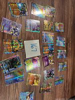 Top view of 24 holographic Pokémon cards spread on wood floor