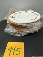 Stack of eight saucers wrapped in plastic with cardboard dividers