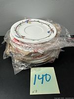 Stack of eight wrapped saucers showing floral rim pattern