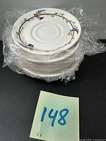 Stack of eight saucers still in plastic wrap