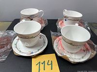 All four teacup and saucer sets, some still in original plastic wrap