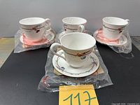 Front view of four wrapped teacup and saucer sets