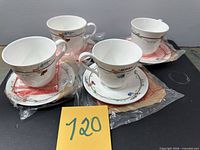 Four teacups on saucers, packaging visible