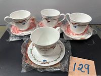Four teacups and four saucers, most still in factory plastic wrap