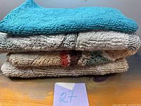 Stacked view of four bath mats showing teal, beige shag, patterned and grey textures