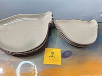 Stack of six beige rooster-shaped ceramic platters