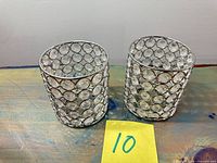 Two cylindrical crystal-inset metal trim covers on tabletop