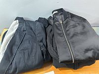 Three black outerwear pieces stacked