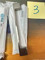 Single brushed nickel cabinet pull removed from packaging shown beside wrapper