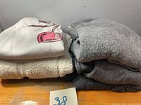 Stack of four folded sweaters showing colors and textures