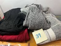 Stack of four sweaters showing colours and knit patterns