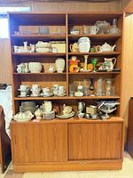 Front view showing upper open shelving filled with dishes and lower sliding doors