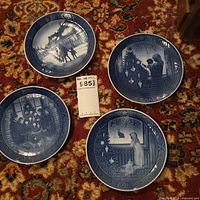 Four Royal Copenhagen blue-white Christmas plates displayed on carpet