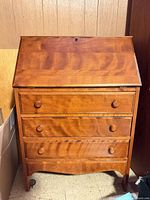 Front view showing three drawers and drop-front surface